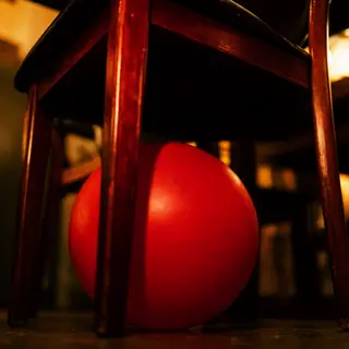 A red ball underneath a wooden chair
