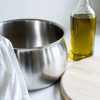 A kitchen counter with a stainless steel pot, a wooden cutti
