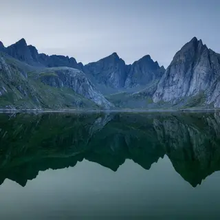 A mountain range reflected in a still alpine lake, with the 