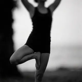 A person in a yoga tree pose — standing on one leg with the 