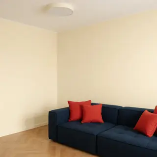 A minimalist room with walls in #F5E6CC (warm cream), a sofa