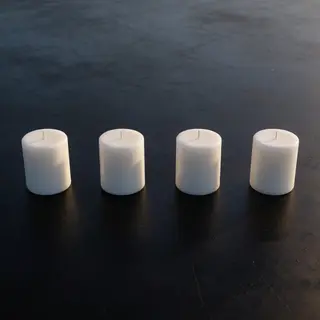 Exactly 4 white candles standing on a dark surface