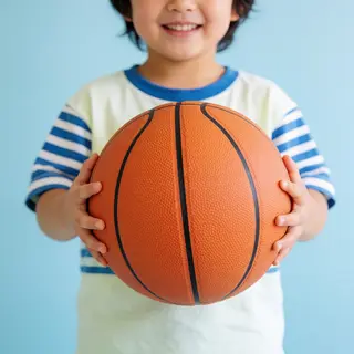 A child holding a basketball, both at correct relative sizes