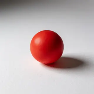 A red sphere on a white surface with a single shadow cast to