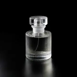 A clear glass perfume bottle on a reflective black surface w