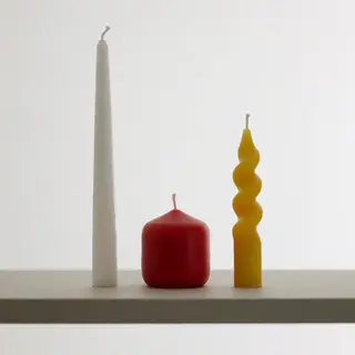 A tall thin white candle, a short fat red candle, and a medi