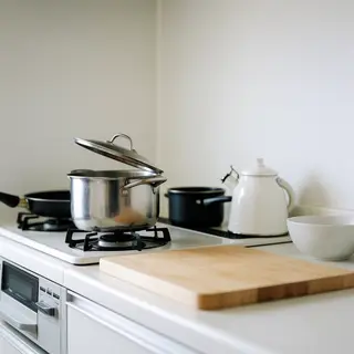 A kitchen with pots, pans, a stove, and a cutting board but 