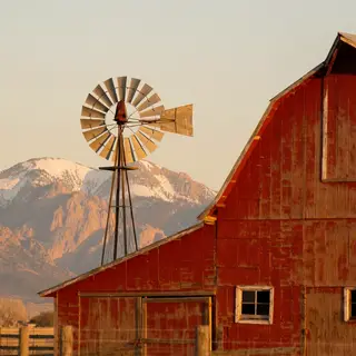 A landscape with a red barn in the foreground at large scale