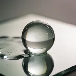 A clear glass sphere sitting on a mirror surface near a pool