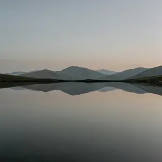 A mountain range reflected in a still alpine lake, with the 