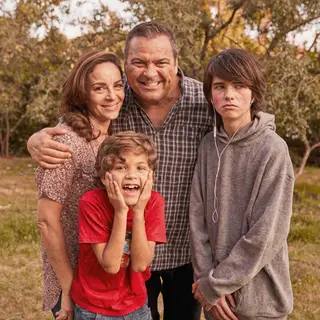 A family photo with four people: a father beaming with pride