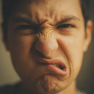 A close-up of a person's face showing clear disgust, nose wr