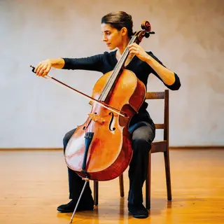 A cellist seated with correct posture, legs around the instr
