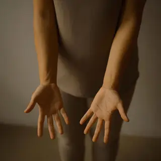 A person standing with both hands visible at their sides, fi