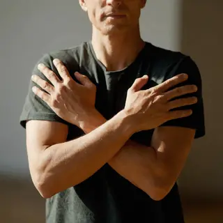 A man with arms crossed, both hands resting on opposite uppe