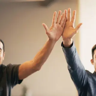 Two people doing a high-five, palms meeting with all fingers