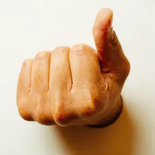 A hand giving a thumbs-up with four fingers curled and thumb