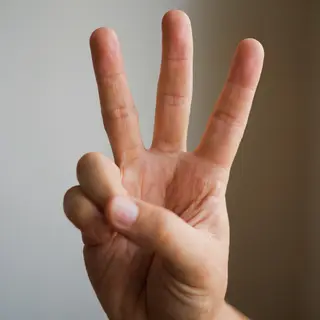 A person counting to three on their fingers, with index, mid