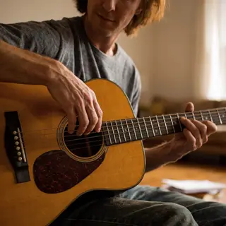 A person playing an acoustic guitar with left hand on the fr