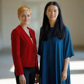 Two women standing side by side: one with short blonde hair 