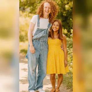 Two friends posing: one tall with curly red hair in denim ov