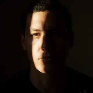 A portrait with dramatic split lighting — half the face brig