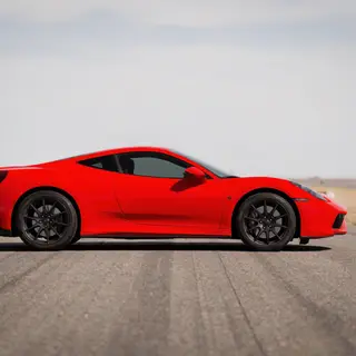 A bright red sports car parked on a gray asphalt road — the 