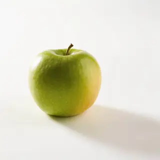 A ripe green apple on a seamless white background with soft 
