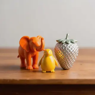 An orange elephant, a yellow penguin, and a silver strawberr