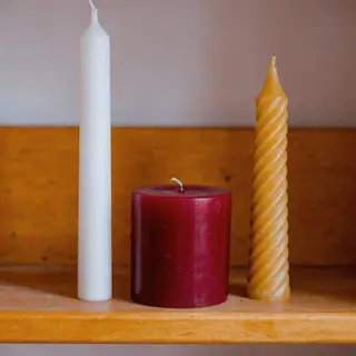 A tall thin white candle, a short fat red candle, and a medi