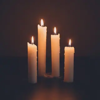 Exactly 4 white candles standing on a dark surface