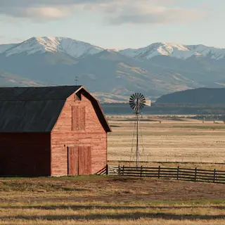 A landscape with a red barn in the foreground at large scale