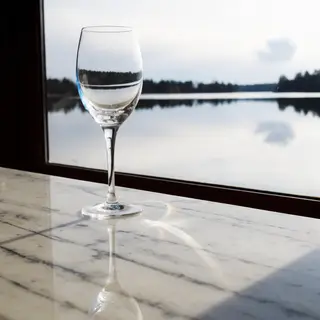 A crystal wine glass on a polished marble counter next to a 