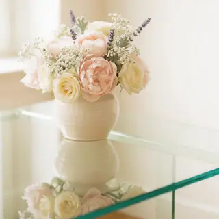 A vase of flowers on a glass table with a clear reflection v