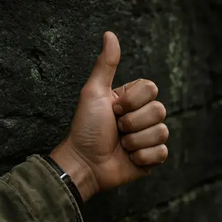 A hand giving a thumbs-up with four fingers curled and thumb