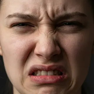 A close-up of a person's face showing clear disgust, nose wr