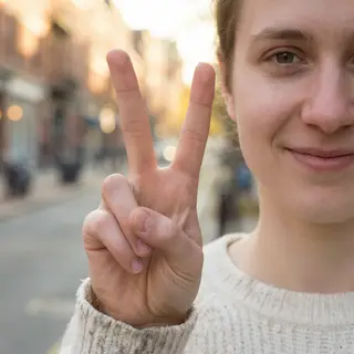 A person making a peace sign with their right hand, clearly 