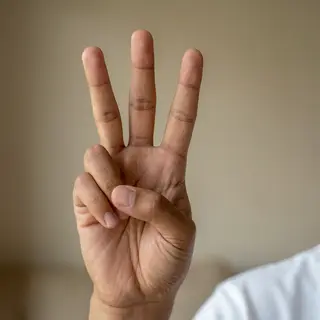 A person counting to three on their fingers, with index, mid