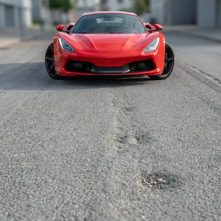 A bright red sports car parked on a gray asphalt road — the 