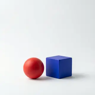 A red ball and a blue cube sitting side by side on a white s