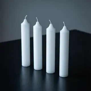 Exactly 4 white candles standing on a dark surface