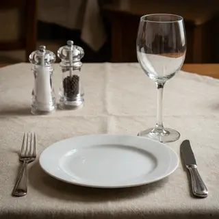 A dinner table scene with a plate, fork, knife, wine glass, 