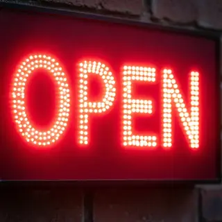 The word 'OPEN' displayed on a red LED sign with glowing pix