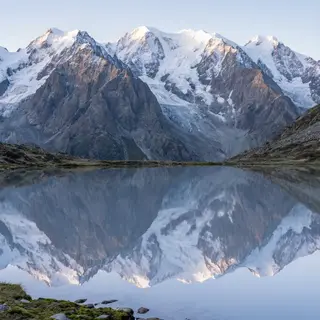 A mountain range reflected in a still alpine lake, with the 