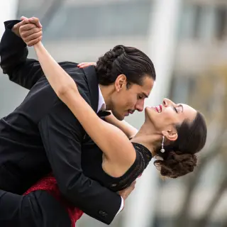 Two tango dancers in a close embrace, the man dipping the wo