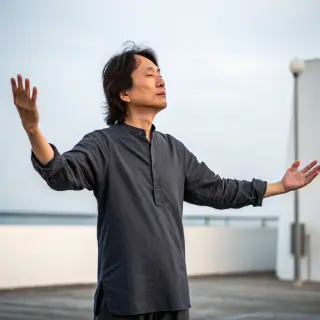 A person standing with both hands visible at their sides, fi