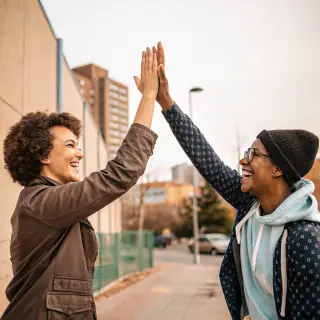 Two people doing a high-five, palms meeting with all fingers
