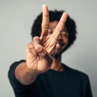 A person making a peace sign with their right hand, clearly 