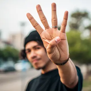 A person counting to three on their fingers, with index, mid
