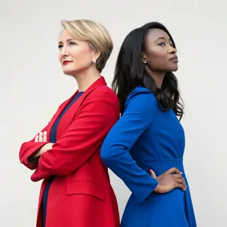Two women standing side by side: one with short blonde hair 